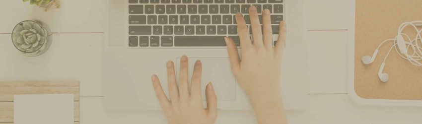 Praxis für Hypnose auch online geöffnet: Hände bedienen MacBook Tastatur und Trackpad. Büro Tisch mit Utensilien